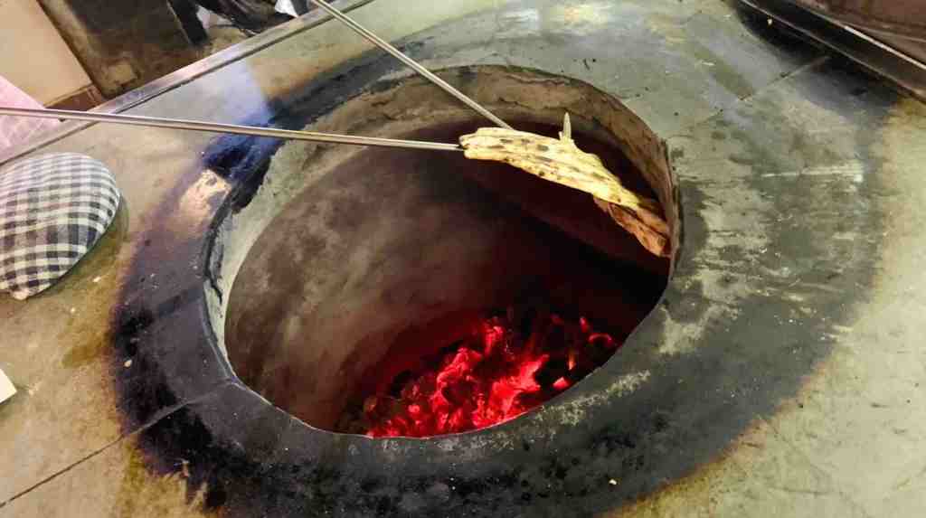Naan bread cooking in a hot tandoor oven
